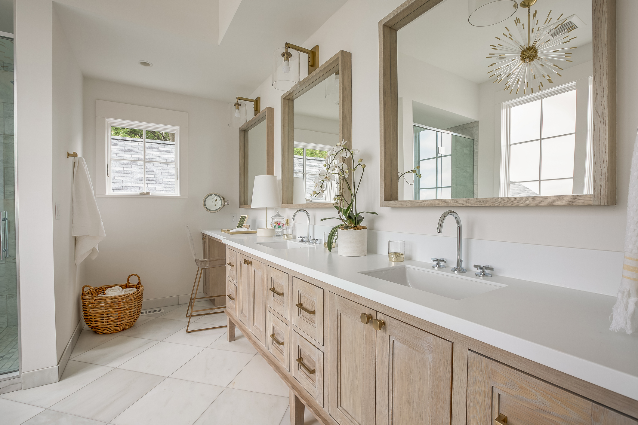 Remodeled bathroom with white tile floor, light wood cabinets, white stone countertop, dual vanity, white walls.